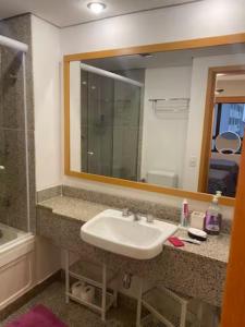 La salle de bains est pourvue d'un lavabo et d'un grand miroir. dans l'établissement Flat com sacada e piscina, à São Paulo