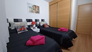 two beds in a room with pink pillows at Vivienda Uso Turístico Las Gemelas de Arevalo in Arévalo