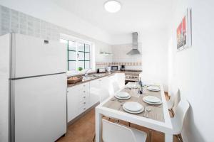 Biała kuchnia ze stołem i lodówką w obiekcie Villa Fula w mieście Playa Blanca