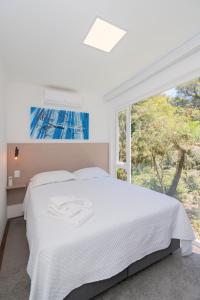 a white bedroom with a bed and a window at KŌN - Pousada Romântica in São Francisco de Paula