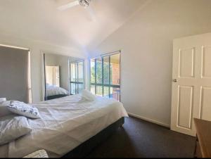 a bedroom with a white bed and a window at Coconuts - 3 bedroom 3 bathroom townhouse with tennis court in Nelson Bay