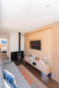 a living room with a couch and a tv on a wall at KŌN - Pousada Romântica in São Francisco de Paula