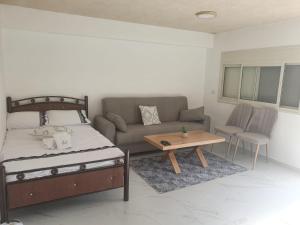 a bedroom with a bed and a couch and a table at צימר נתיב המעיין in Ein Kinya