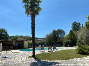 a palm tree and chairs next to a swimming pool at Charmant Studio avec Piscine Privative sur 1500m2 de Terrain Proche Cascade de Sillans VAR Verdon in Sillans-la Cascade