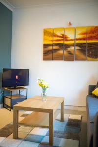 a living room with a coffee table and a painting at Comfy 3 bedroom cottage super fast wifi, paid parking in Reading