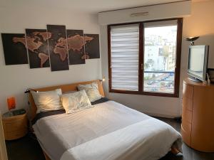 Schlafzimmer mit einem Bett, einem Fenster und einem TV in der Unterkunft Issy - les jardins du séminaire in Issy-les-Moulineaux