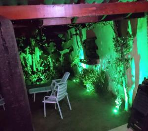 Hospedagem Maria Joana في أتيبايا: حوض للأسماك وكرسي في غرفة ذات أضواء خضراء
