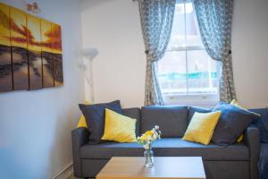 a living room with a blue couch with yellow pillows at Comfy 3 bedroom cottage super fast wifi, paid parking in Reading