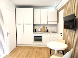 a kitchen with white cabinets and a white table at Bright Tiny Studio - Shared Pool & Sauna - Free Parking - Air condition in Muralto