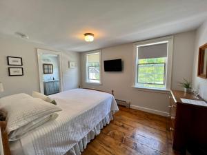 a bedroom with a white bed and two windows at The Griff Inn in Waitsfield