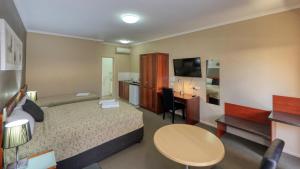 Habitación de hotel con cama y escritorio en Top of the Town Motel & Apartments en Benalla