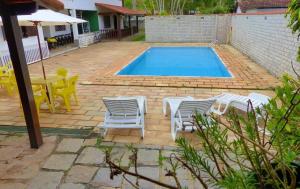 a swimming pool with white chairs and a table and a table and chairsitures at Espaço 579 in Miguel Pereira