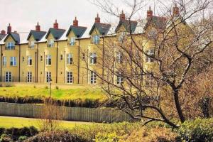 un gran edificio amarillo con una valla delante en The Folly Bushmills, en Bushmills