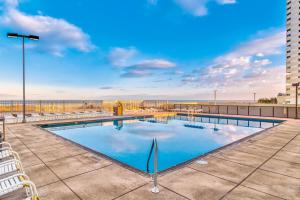 Una piscina con sillas y el océano al fondo. en Golden Sands 714, en Ocean City