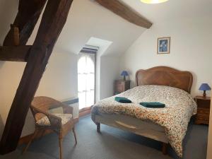 sypialnia z łóżkiem, krzesłem i oknem w obiekcie Les Granges du Bois Normand 