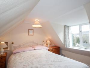 a bedroom with a bed and a window at Rose Cottage in Strathpeffer