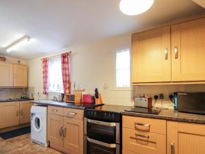 a kitchen with wooden cabinets and a stove top oven at Rose Cottage in Strathpeffer