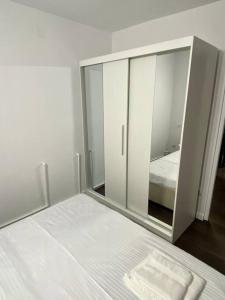 a white bedroom with a bed and a mirror at EDA apartment in Bistriţa