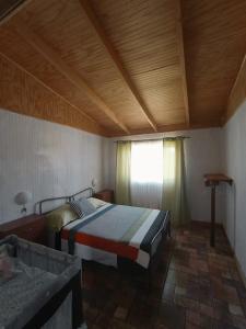 a bedroom with a bed with a wooden ceiling and a window at Parcela Sant Llorenç in Cabrero