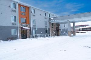 um edifício de apartamentos com um posto de gasolina na neve em AmericInn by Wyndham Madison WI em Madison