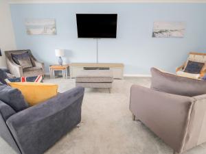 a living room with three couches and a tv at Bay Lodge in Amlwch