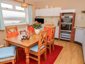 a kitchen and dining room with a wooden table and chairs at Bay Lodge in Amlwch