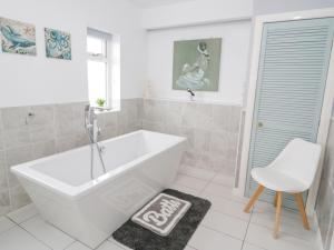 La salle de bains blanche est pourvue d'une baignoire et d'une chaise. dans l'établissement Bay Lodge, à Amlwch 27 autres photos