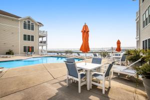 a patio with a table and chairs and a pool at Laguna Bay - 37292 Lighthouse #201 in Selbyville