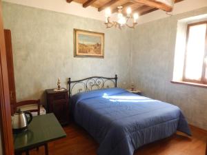 a bedroom with a blue bed and a table and a window at Agriturismo Fonte Magria in Abbadia San Salvatore