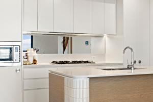 a white kitchen with a sink and a refrigerator at 3 Bedroom Apartment over looking Newcastle in Newcastle