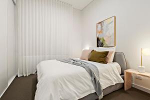 um quarto branco com uma cama e uma fotografia na parede em 3 Bedroom Apartment over looking Newcastle em Newcastle