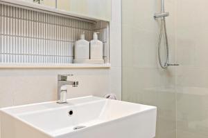 a white bathroom with a sink and a shower at 3 Bedroom Apartment over looking Newcastle in Newcastle