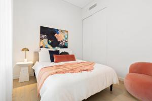 a white bedroom with a bed and a orange chair at 3 Bedroom Apartment over looking Newcastle in Newcastle