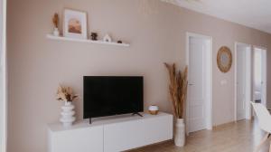 uma sala de estar com uma televisão de ecrã plano numa parede branca em Casa Mahalo - Modern Apartment with Pool, Minutes from Spectacular Beaches em Parque Holandes