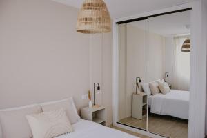 ein weißes Schlafzimmer mit einem Spiegel und einem Bett in der Unterkunft Casa Mahalo - Modern Apartment with Pool, Minutes from Spectacular Beaches in Parque Holandes