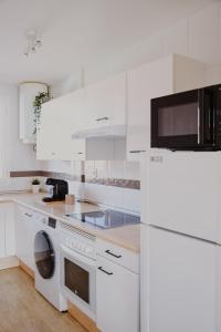 eine weiße Küche mit einem Kühlschrank und einer Waschmaschine in der Unterkunft Casa Mahalo - Modern Apartment with Pool, Minutes from Spectacular Beaches in Parque Holandes