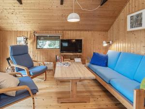 ein Wohnzimmer mit einem blauen Sofa, einem Tisch und Stühlen in der Unterkunft 4 person holiday home in Martofte in Martofte