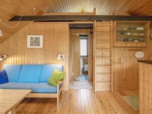 ein Wohnzimmer mit einem blauen Sofa und Holzwänden in der Unterkunft 4 person holiday home in Martofte in Martofte