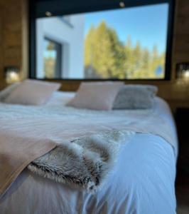 a bed with a white comforter with a large screen at ATPeak Lodge Maison de Montagne d'exception in Xonrupt-Longemer