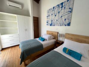 a bedroom with two beds and a painting on the wall at Ride On Beach House in Nosara