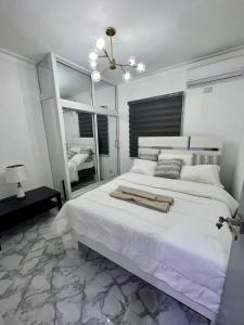 a white bedroom with a large bed and a mirror at Acogedor apartamento 2 hab Distrito nacional, próximo agora mall in Santo Domingo