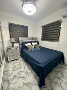 a bedroom with a blue bed and a night stand at Acogedor apartamento 2 hab Distrito nacional, próximo agora mall in Santo Domingo