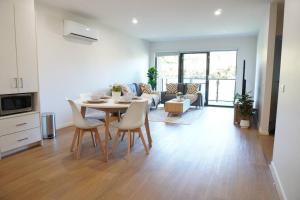 a kitchen and living room with a table and chairs at ViQi Two bedroom apartment front of century walk Including Premium NETFLIX & Prime AMAZON with 75 INCH TV in Glen Waverley