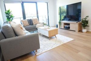 sala de estar con sofá y mesa de centro en ViQi Two bedroom apartment front of century walk Including Premium NETFLIX & Prime AMAZON with 75 INCH TV, en Glen Waverley