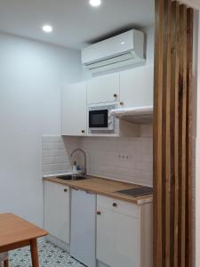 a white kitchen with a sink and a microwave at Torre de Ambroz in Plasencia