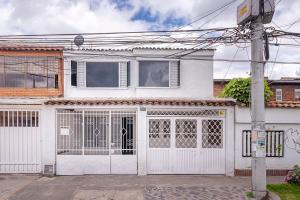 una casa blanca con una puerta blanca en Ayenda Hostal El Tocororo, en Bogotá