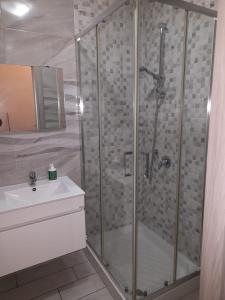um chuveiro com uma porta de vidro ao lado de um lavatório em ArenHouse em Nápoles