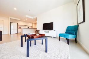 a living room with a table and a blue chair at Tranquility the Beach in Huskisson