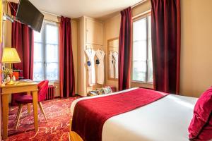 a hotel room with a bed and a desk and windows at Romance Malesherbes by Patrick Hayat in Paris