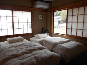 2 camas en una habitación con 2 ventanas en ゲストハウスみちしお 